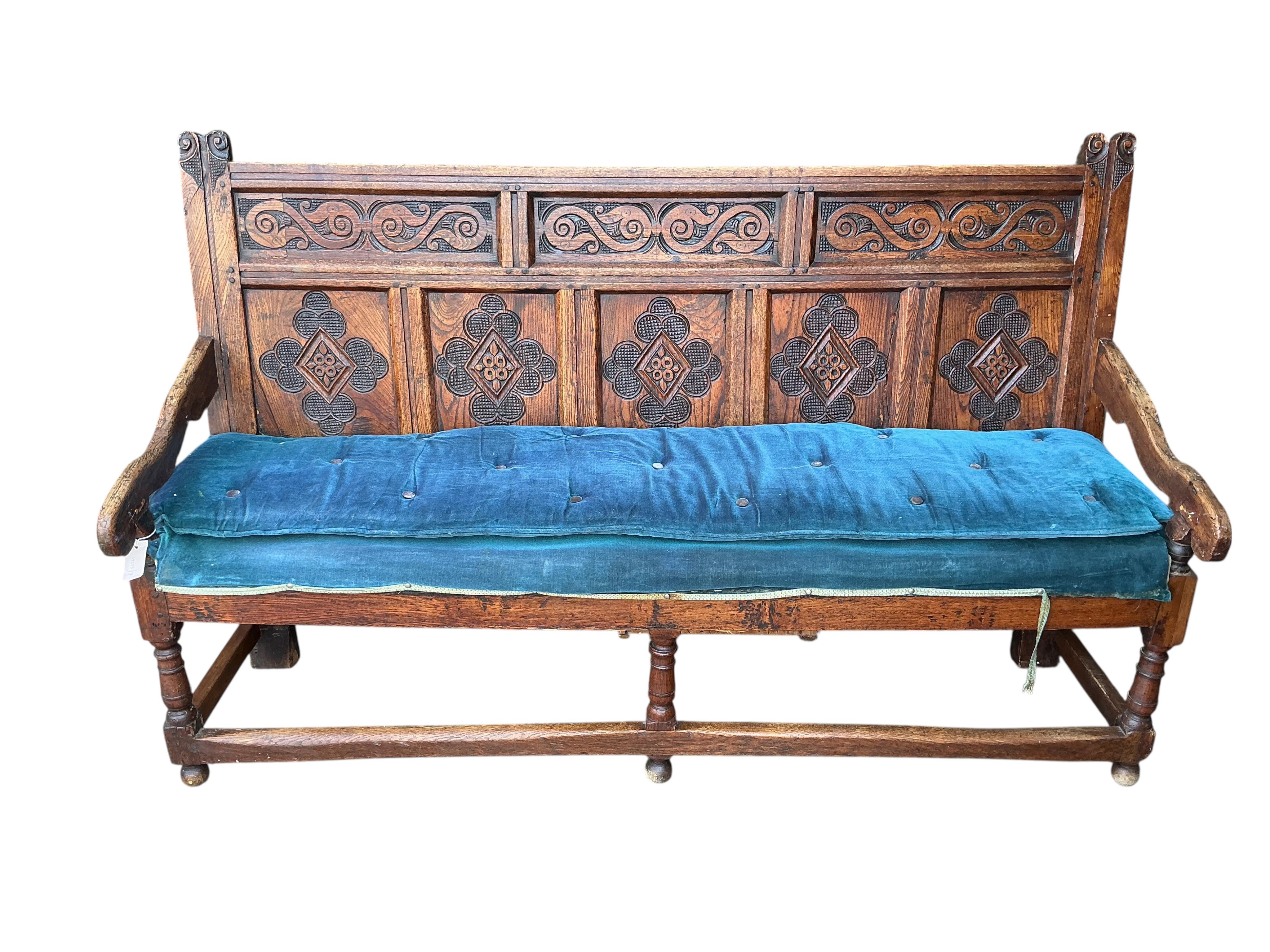 An 18th century panelled oak settle, later carved, width 177cm, depth 55cm, height 110cm